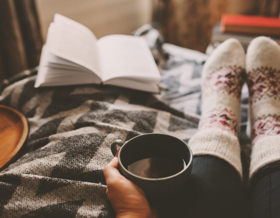 cozy winter day at home with cup of hot tea, book and warm socks. Spending weekend in bed, seasonal holidays