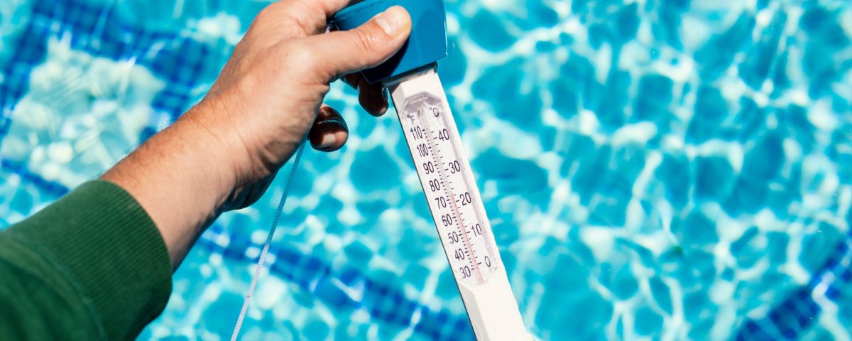 Reading a water thermometer in swimming pool, checking water